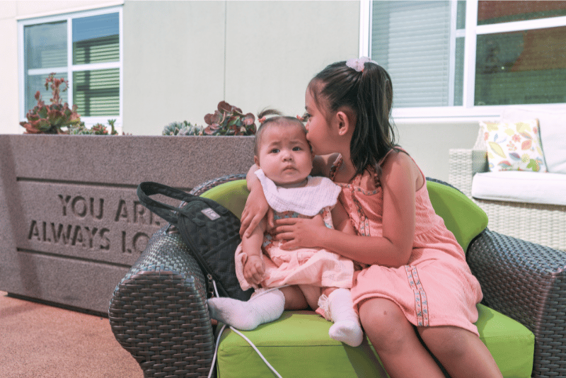 Big sister Rylee kissing her infant sister Remi at Ronald McDonald House San Diego
