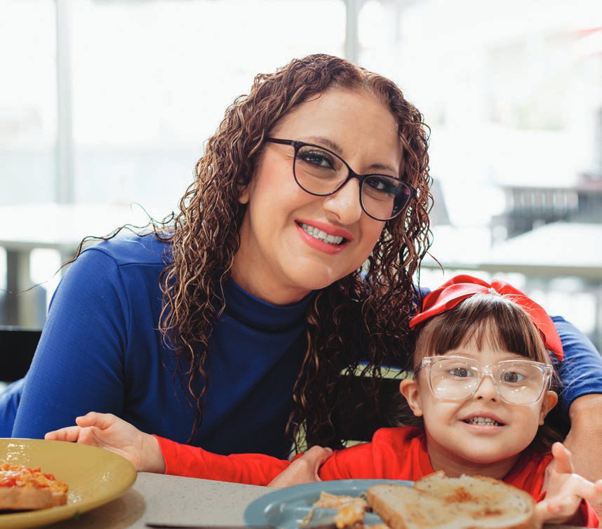Berenice smiles with her young daughter Nicolette at the dinner table.