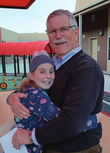 Chuck Day hugs a smiling young girl, Caitlin, outside the House.