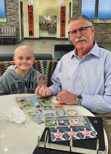Chuck Day sits with a young boy, Christopher, at a table at the House.