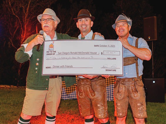 Chuck Day and the Dinner with Friends founders hold an oversized check celebrating the milestone.
