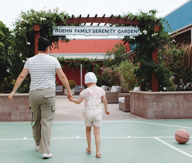 A parent and young child walk hand in hand toward the Rohde Family Serenity Garden at Ronald McDonald House San Diego.