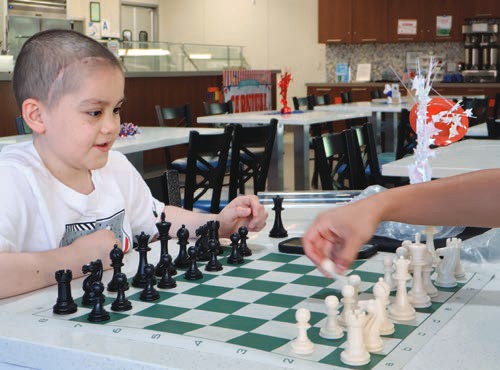 A young boy concentrates on a game of chess at the House.