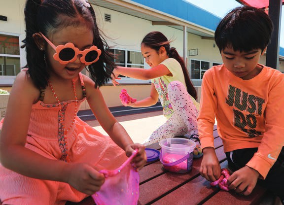 Two young children in party sunglasses laugh during an activity at the House.