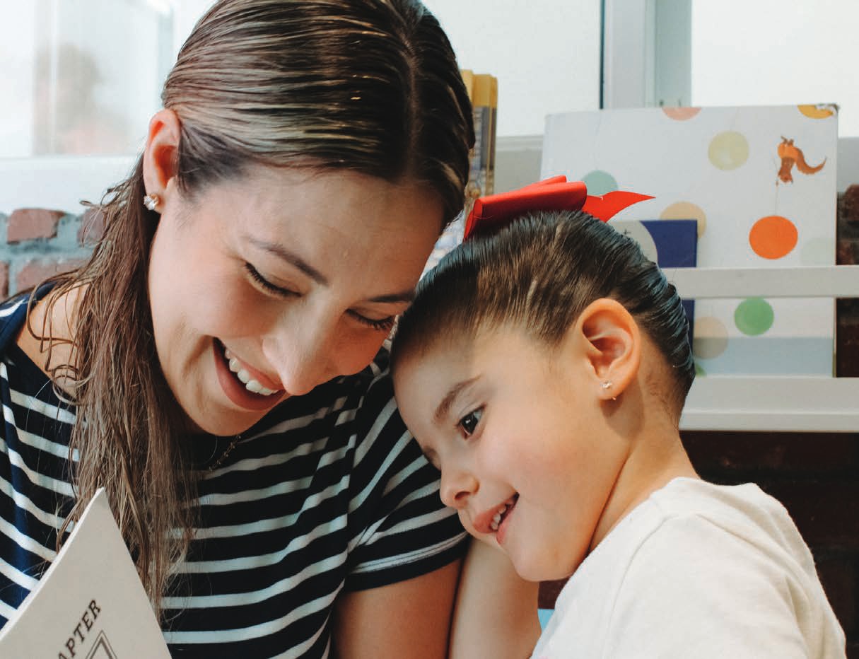 A smiling mother leans close to her young son as they play together.