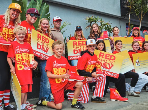 Red Shoe Day volunteers in red shirts and hats hold signs at an intersection collection.
