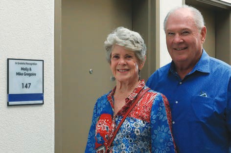 Molly and Mike Gregoire stand beside the plaque for their named guest suite.