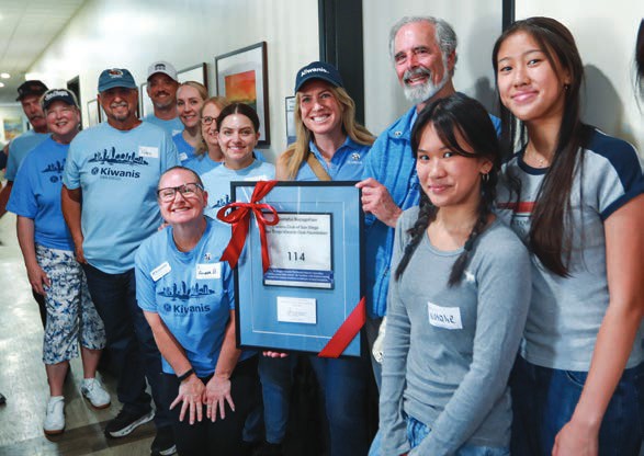 Members of the San Diego Kiwanis Club gather around their named guest suite plaque.