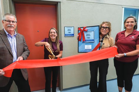 Watkins Wellness representatives cut a red ribbon to open their named guest suite.
