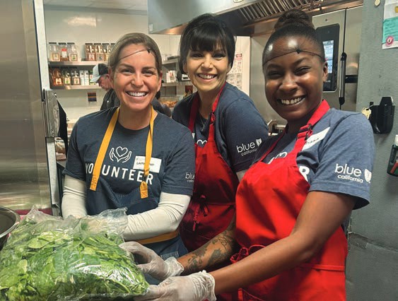 Three smiling volunteers pose together at the House.